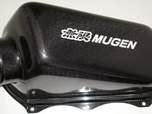 Mugen Intake for the TSX.  This is the airbox cover.  You can
see that this is a newer one and Mugen switched from their
previous gray sticker to this new white one to match their
spark plug cover stickers now.