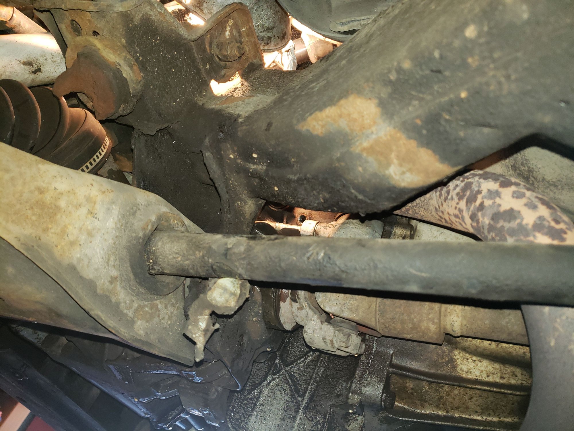 The view from low behind the front brake caliper. The open hole where the plug goes in the block can be seen in the lighted area. The front end of the left-side torsion bar is in the foreground. 