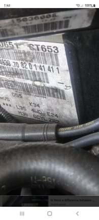 Located to the right of the heater core hoses, directly behind the distributor. Notice the zr2 at the bottom right of the sticker...