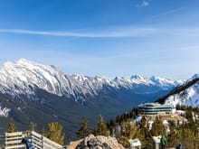 The new terminal for the Banff Gondola taken from Sulphur Mountain Cosmic Ray Station National Historic Site.  The numerous peaks of Mount Rundle on the left.