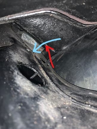 The blue arrow is the top of the frame.  There are three holes.  Does the parking brake cable route thru the roughly 1" diameter round hole shown with the blue arrow.   The red arrow I believe is where the parking brake cable routes through the fire wall.