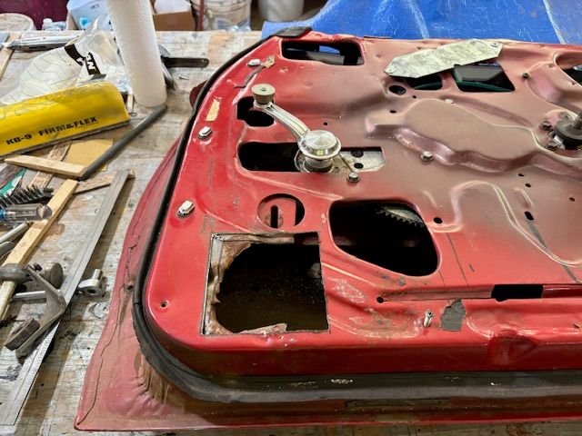 Radio Man put a speaker in this area.  I suspect what happened is that they cut through the finish interior door panel and were then committed to the speaker position.  Little did they know that there is a substantial piece of 12 gauge steel reinforcement beneath the 20 gauge door Sheetmetal.  It turned into a real mess for them.
