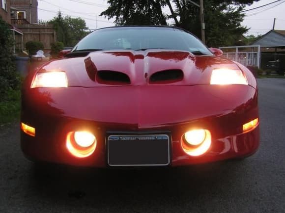 Front View Showing:
-The Custom Fully Functional Ram Air Hood (From the 2002 WS6 Style Body) with Custom Ram Air Box

-One of a kind Custom Headlights (100 watt bulbs in each)

-Clear Diamond-Cut Front and Rear Sidemarker lights (Lights are clear when off, but light up yellow in the front and red in the rear when lights are on)

-NEW Red Paint (Original Color)~ $2000 

- New Trans Am Front Bumper, Rear Bumper, Fenders, Ground Effects