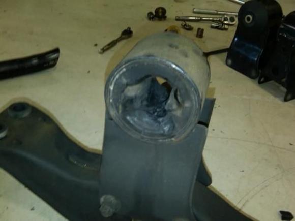 Stock motor mounts off car. Stock mount completely butchered. Urethane mounts in background.