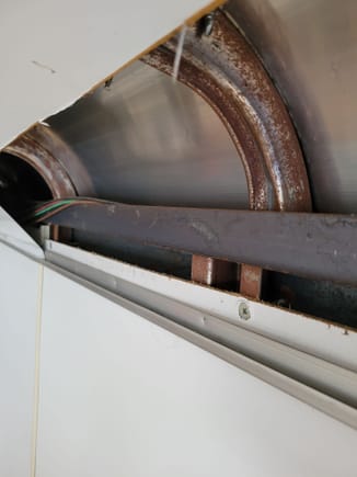 Roof and wall beams are bare steel and rusty. Wires wrap over the metal edge with no protection. 