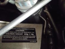 850 Grams of R-134.  Sticker is on RHS shock tower.