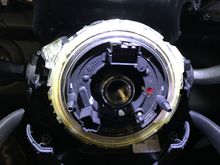 Clock spring is held in place with clips. Once you unbutton the yellow clip on the back right top corner