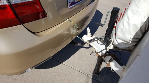 On my previous es300 sedan I drilled a hole to feed the wire harness under the car. I prefer this method.    It's more convenient to pull it out of the trunk.   The chance of it dragging on the ground is also reduced.