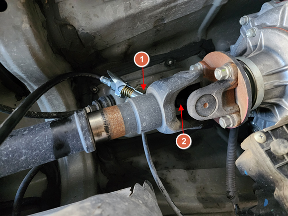 Here's another angle of the rear drive shaft behind the transfer case. The LockNLube quick detach/attach is at a weird angle going up and over, but it was very doable for the slide yoke zerk (1). The quick detach/attach was too long however to slide into and reach the spider U-joint (2).