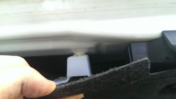 There are 2 white (1 on each side of latch assembly) that are holding the trim panel on to trunk lid just below the license plate position.