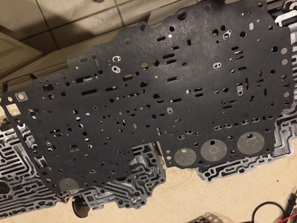 One of the gaskets lined up with the bare separator plate. Some of the valve body passages are bleeding through the holes in the image but it lines up dead nuts perfect.