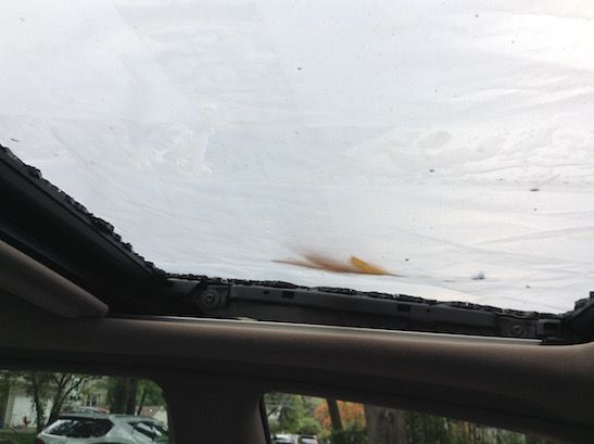 Looking up at the broken moon roof. Removal of the trim allows you to see two of the four screws that need removal with a T25 screwdriver. Clean out the broken glass from tracks and grease before dropping new glass unit into place. Loosely screw into place and adjust height of glass so that it is level with top of car, then tighten screws.