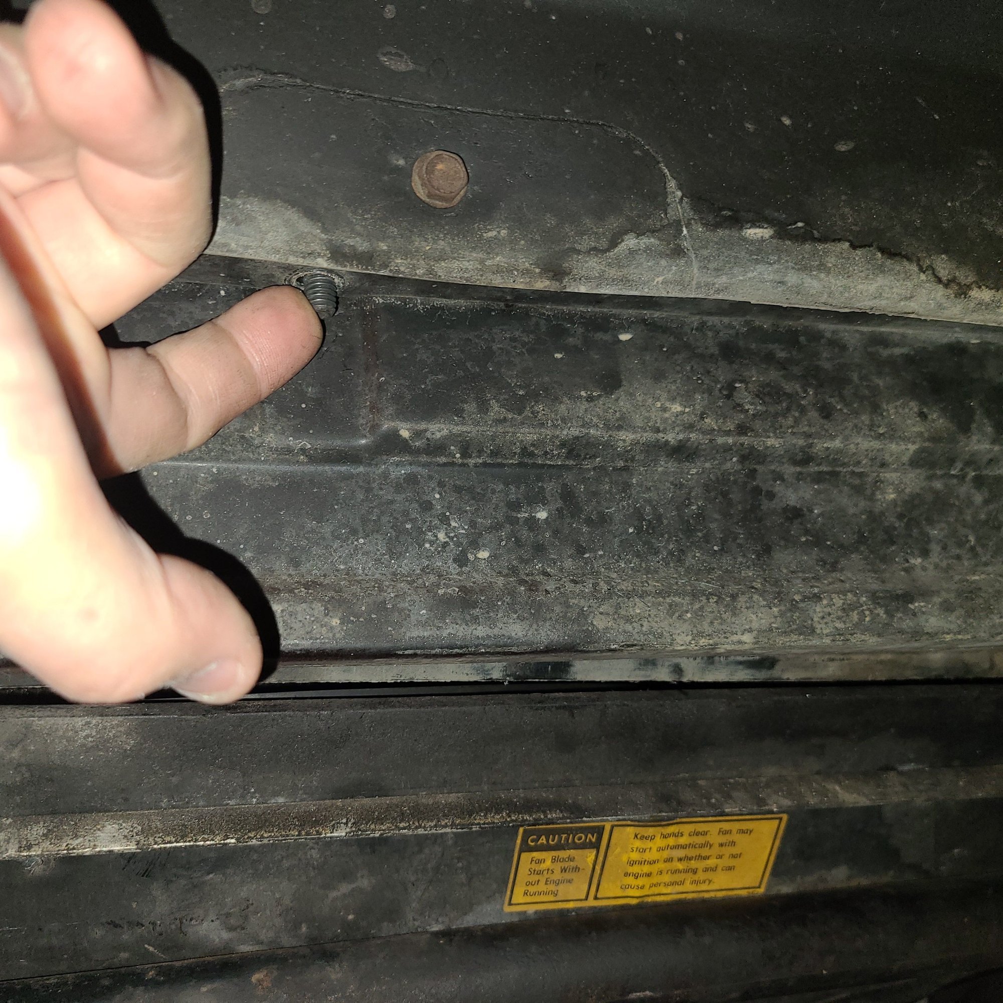This is under the car in the center of the radiator support.  It had a nut on it that I have removed.  You might be able to just loosten it a bit but your call.