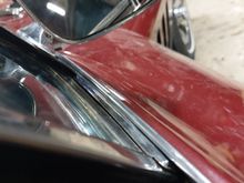 Tab on the back of the bracket slips behind the weatherstripping. Carefully slip a wedge in to open a gap if none exists to slide the tab down.