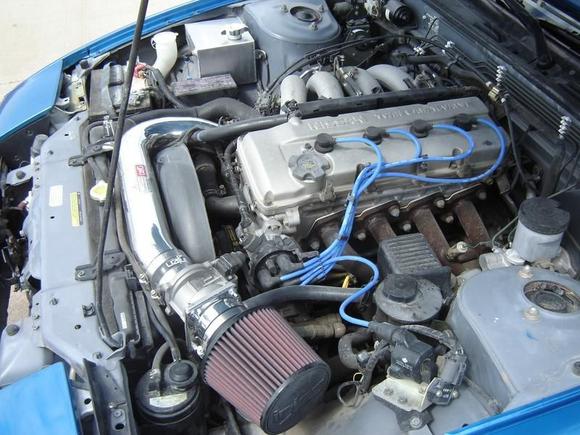 Engine bay, showing the shiny new intake and blue sparkplug wires.
Also shows the rusty P.O.S. header that a previous owner put on it.  Can you believe some dumbass put a 4-1 header on a 4-banger?  The car was gutless below 4000rpm until I replaced that header.