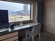 TV and desk with bathroom to right. Facing the bay and the conference centre roof. Fridge to the left