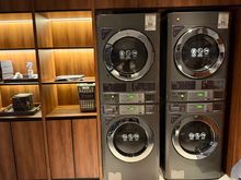2 washers and 2 dryers, with a lot of laundry bags and an iron