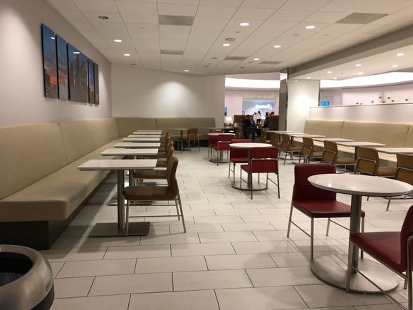 There is a large dining room/cafeteria seating area, which I find curious as the food options are meager.  The outlets/USB ports here are located under the bench seating. Note the overhang - it is difficult to get to these outlets without kneeling. And they are not spaced proportional to the tables, so your outlet may be under the table next to you, making for an awkward situation. You can see the check in desk at the back of the picture.