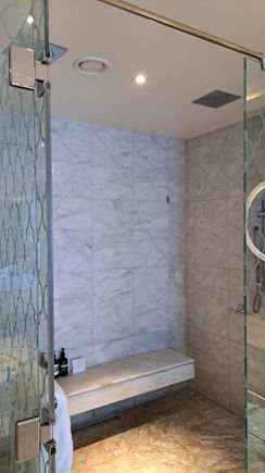 Huge shower room  ( bench and two shower heads). Aesop bottles on bench. Toilet next door ( separate glass  door) and large bath in main bathroom. Window between bathroom and bedroom ( as well as door) but blind can be electronically controlled for more privacy .Bath has a small tv also
