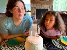 The birthday girls blowing out the candles on a three level Red Velvet cake made by Joyce.