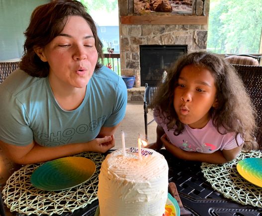 The birthday girls blowing out the candles on a three level Red Velvet cake made by Joyce.