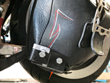Here are the brackets attached, and after a quick spin on my favourite 80KM/H left hand sweeper dragging everything  (that is like 50MpH) , you see the red arrow pointing to them taking the hit instead of the leather.