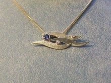 Blue sahpire and diamond set in wave patterned 14k yellow gold