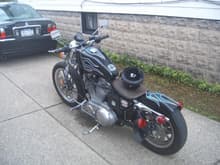 This is the Left rear of my sporty when I got it, I am waiting on the weather to but on the new fender, (not BOBed) I painted the tank and new rear fender flat black. I have a badlander seat, and chrome batterybox and triangle thing. Still waiting on Wide whitewall tires already ordered