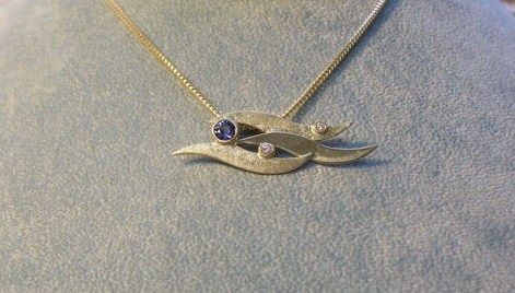 Blue sahpire and diamond set in wave patterned 14k yellow gold