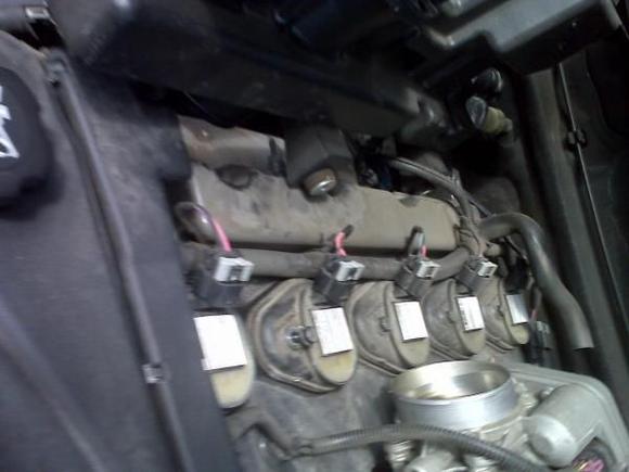 After removing the long and short air hose and 2 mounting bolts holding the plenum, it can be moved out of the way. There is a drainback hose in the rear on a barbed fitting that can just be pulled off to completely remove the plenum. Here are the ignition modules under the plenum.