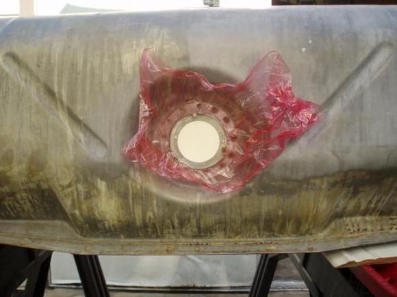 The interior of the tank needs to cleaned as well.  This pic and the following few demonstrate how to seal the various openings on the tank in order to use the rust removal solution on the interior of the tank.  In this pic, for the sending unit opening, cut a piece of cardboard that has the same thickness of the sending unit, I had to use two or three pieces to get the desired thickness.  Place a piece of plastic wrap first to protect the cardboard, then insert the cardboard, followed by the retaining ring used for the sending unit.  This opening is the one used for adding the solution and rinsing the interior of the tank.