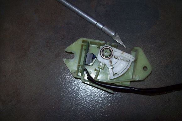 White spring loaded ratchet mechanism as switch actuator, in fully compressed condition.