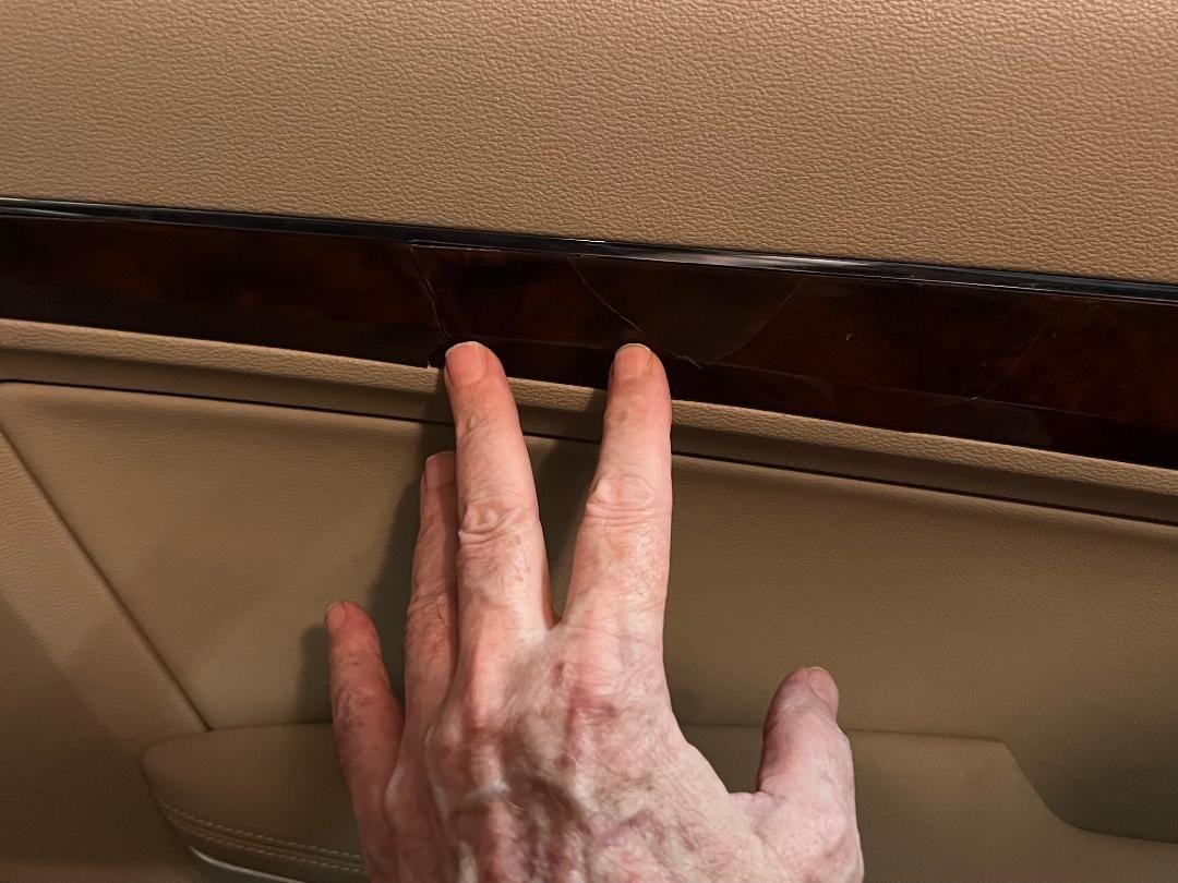 Two fingertips point to the two cracks on pass side door trim.