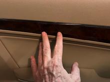 Two fingertips point to the two cracks on pass side door trim.