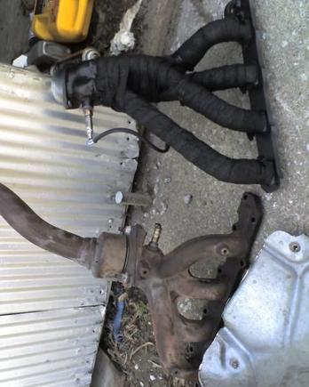 Ceramic coated header with exhaust wrap and black sealer spray coating compared to the stock cast exhaust manifold.