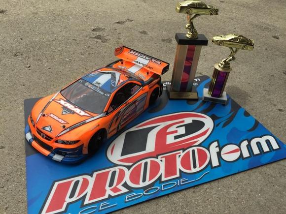My Xray and its Invitational trophies!  I'm running an ORCA TX 17.5, Orion R10 Pro US Stock Spec ESC, Savox 1252 low-profile servo, Reedy 5500 60C lipo, Protoform Mazda Speed6 body, and Contact RC foam tires.  Controlled by a KO Propo EX1-KIY