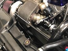 As my fellow sidewinder turbo manifold owners can attest. they vibrate and buzz and its annoying. I came up with a clever way to deal with it that is flexible, applies continuous pressure, and is easily replaceable. 

I am using a hood dampener and an engine torque brace. The Vband clamp is temporary, i'll have someone weld in a tab for it to attach to soon. 
