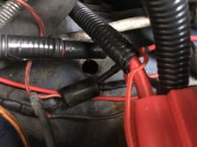 Here the black cylinder connector from the original harness is in place.  Orange and black wire on left side are factory and unchanged.   Wires on the right are cut and re-routed.  The one that used to run straight to the battery terminal is now connected to a fusible link that provides power to the auxiliary cooling fan which operates off a temperature switch in the upper radiator hose.  The wire that originally connected to the alternator now connects to the third wire on the new harness.