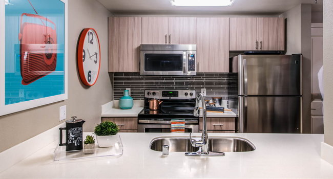 Apartment kitchen with stainless steel appliances, quartz countertops and wood-style flooring.